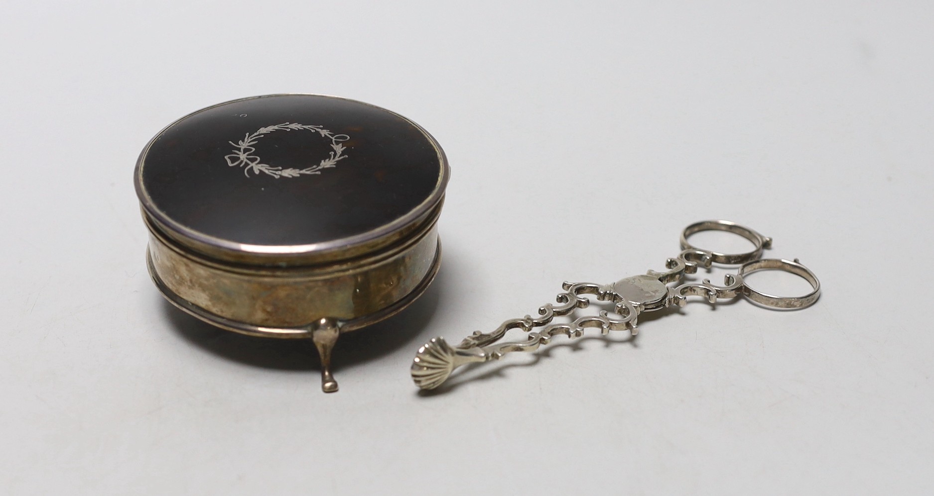 A George V silver mounted tortoiseshell circular trinket box, Horton & Allday, Birmingham 1919, 81mm, together with a pair of mid 18th century silver sugar nips.